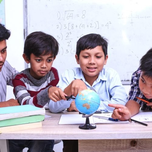 teacher-and-kids-discussing-globe-in-the-classroom-2023-11-27-05-14-37-utc